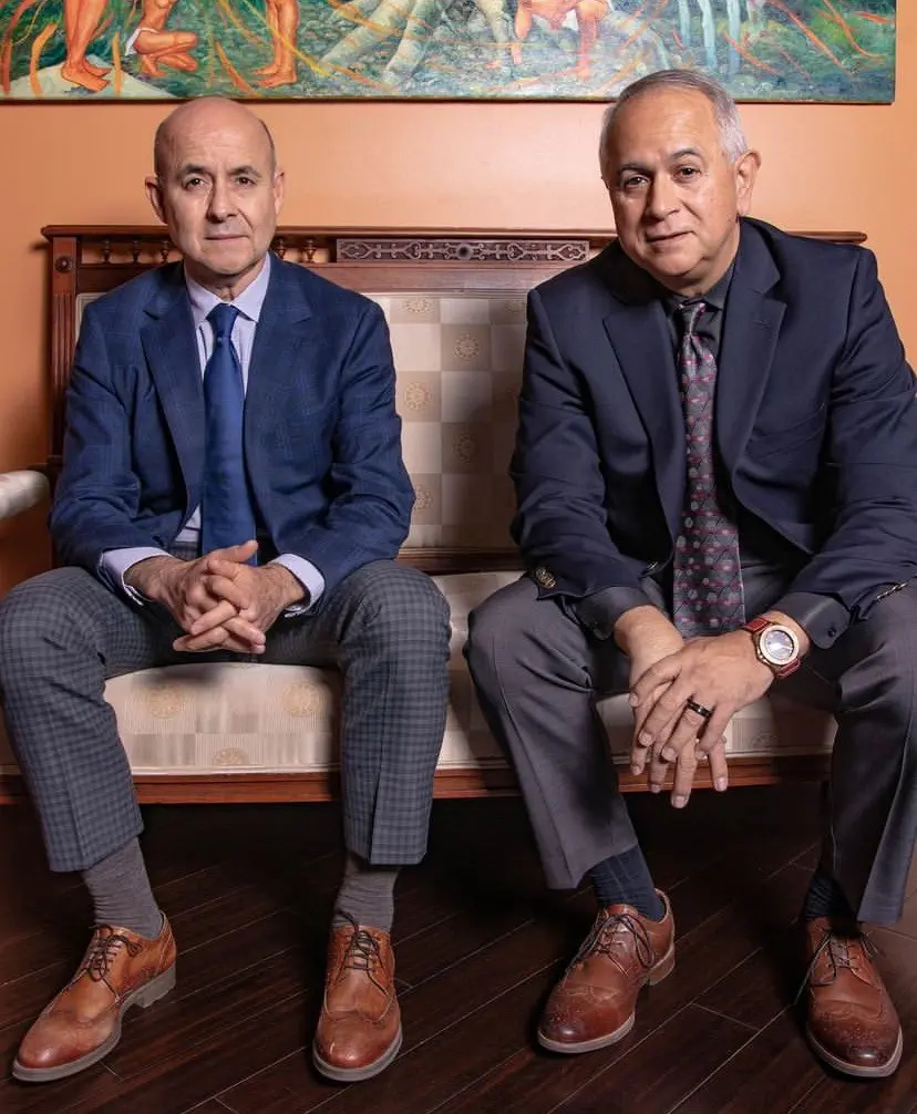 Two men in suits seated on couch