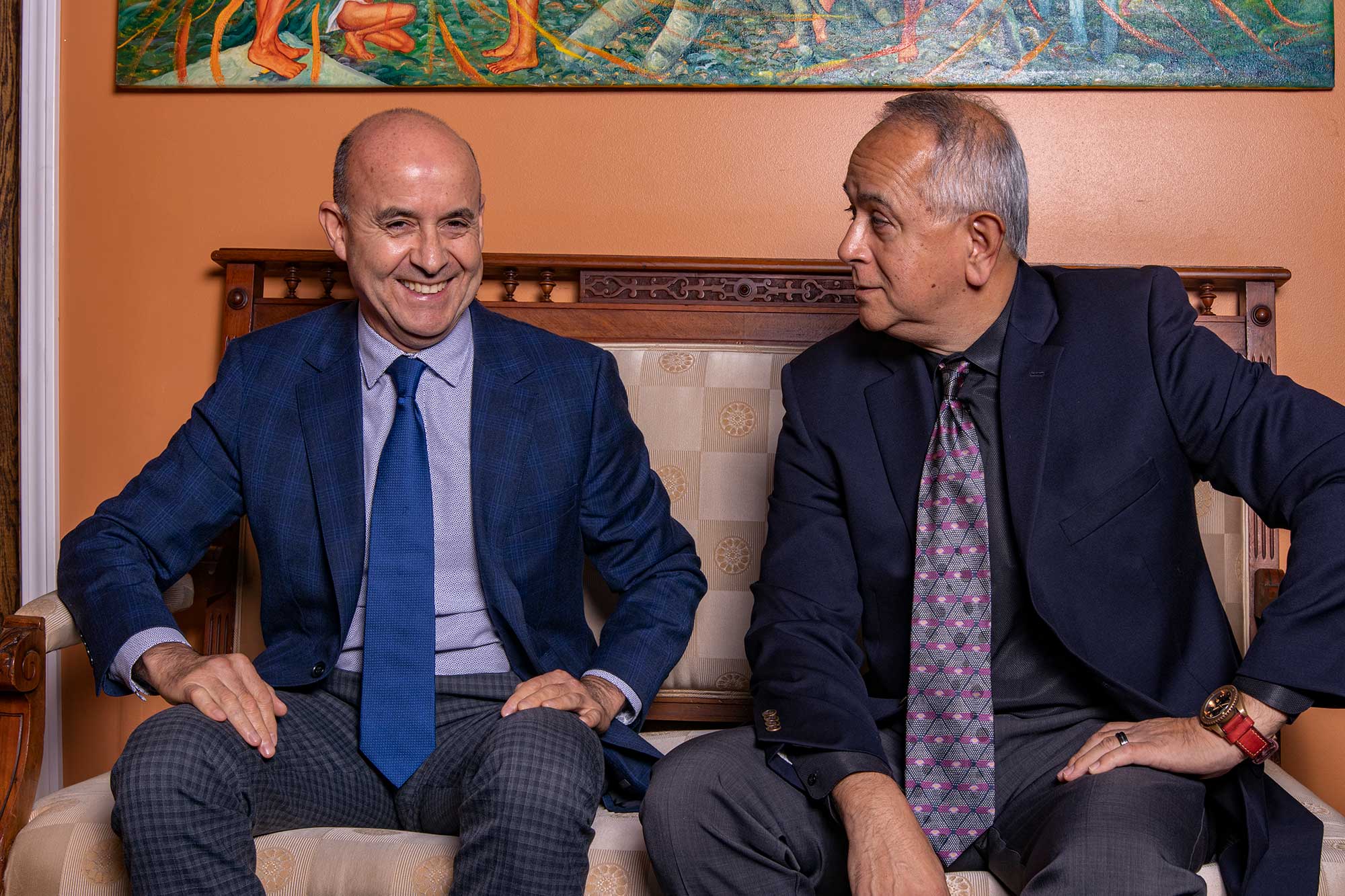 Two men in suits smiling and talking