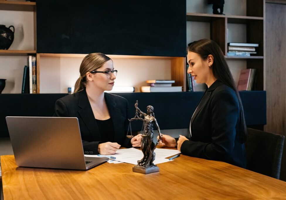 Two women discussing at a wooden table.